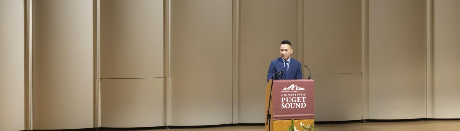 Viet Thanh Nguyen stands at a podium onstage at Schneebeck Concert Hall