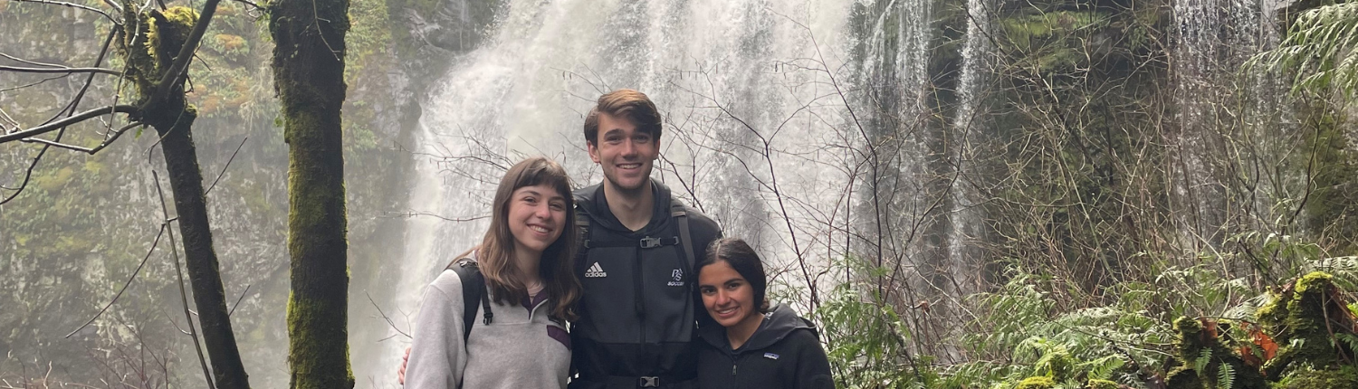 Three people standing in front of a waterfall