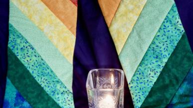 A candle and colorful quilt mosaic