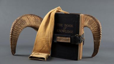 An artist book from the exhibition Science Stories with a dark cover and what appear to be curved horns coming out the sides of the book.