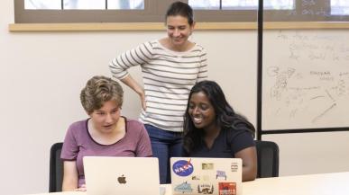 Asst. Prof. Courtney Thatcher and students look at data on a laptop.
