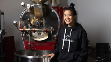 Benita Ki ’11 stands in front of a coffee roaster.