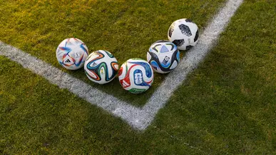 World Cup soccer balls arranged near the a corner on the field.