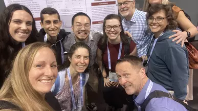 Faculty and students pose in front of a research poster. 