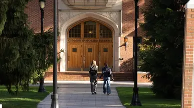students walk in front of the library building