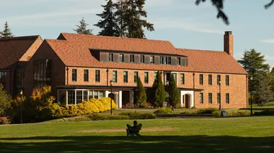 Student sits in an Adirondack chair on Todd Field in front of Thomas Hall.