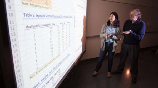 Two faculty members reviewing a spreadsheet projection display