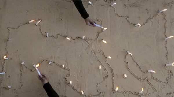 Noor. hands, candles, map of MENA in sand