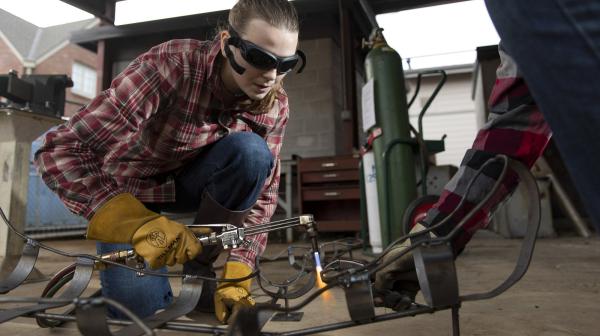 Student using welding equipment to craft a metal sculpture