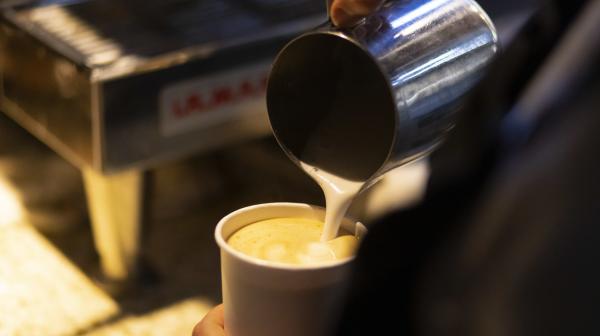 Barista pouring milk into a latte