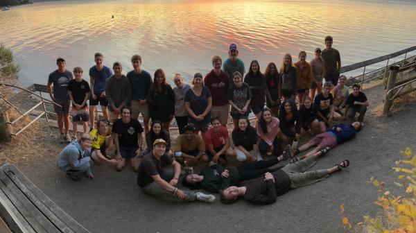 A large group of students pose in front a body of water.