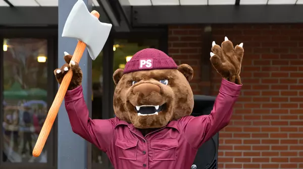 Grizz, the Puget Sound mascot, holding an axe with his hands in the air.