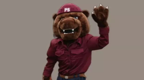 Mascot Grizz waving and wearing maroon shirt and Puget Sound beanie