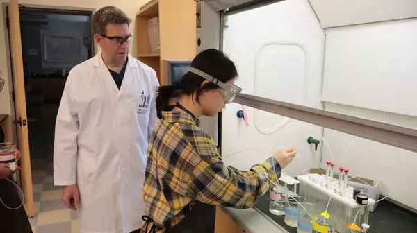 A faculty member supervises a student in the lab.