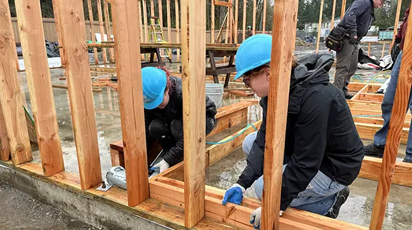 Student volunteers constructing building framing