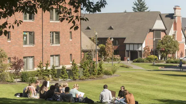 A group of students gathers in the sunshine on one campus' many green spaces.
