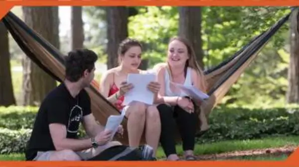 Students relax on campus in a hammock. 