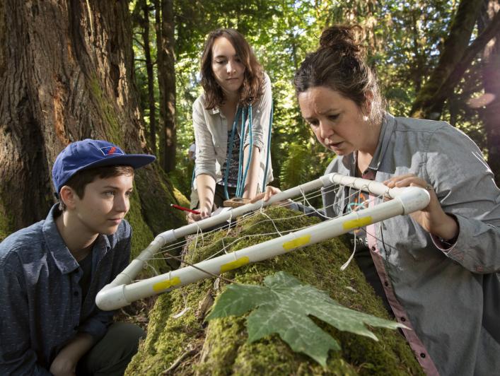 (Left to right) Anna Marchand ('19), Kaela Hamilton ('20), and Dr. Carrie Woods, an assistant professor in the biology department, huddle around a quadrat to measure the abundance of organisms on a nursing log in Pt. Defiance Park, Thursday, July 26, 2018. The group spent three weeks in the Olympic National Park conducting research in the forest canopy.