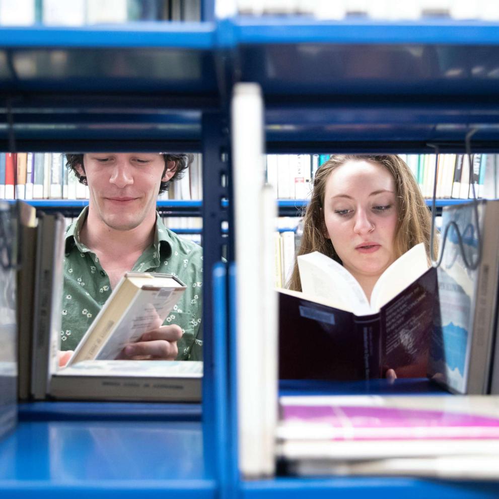 Two students peruse books in Collins Memorial Library.