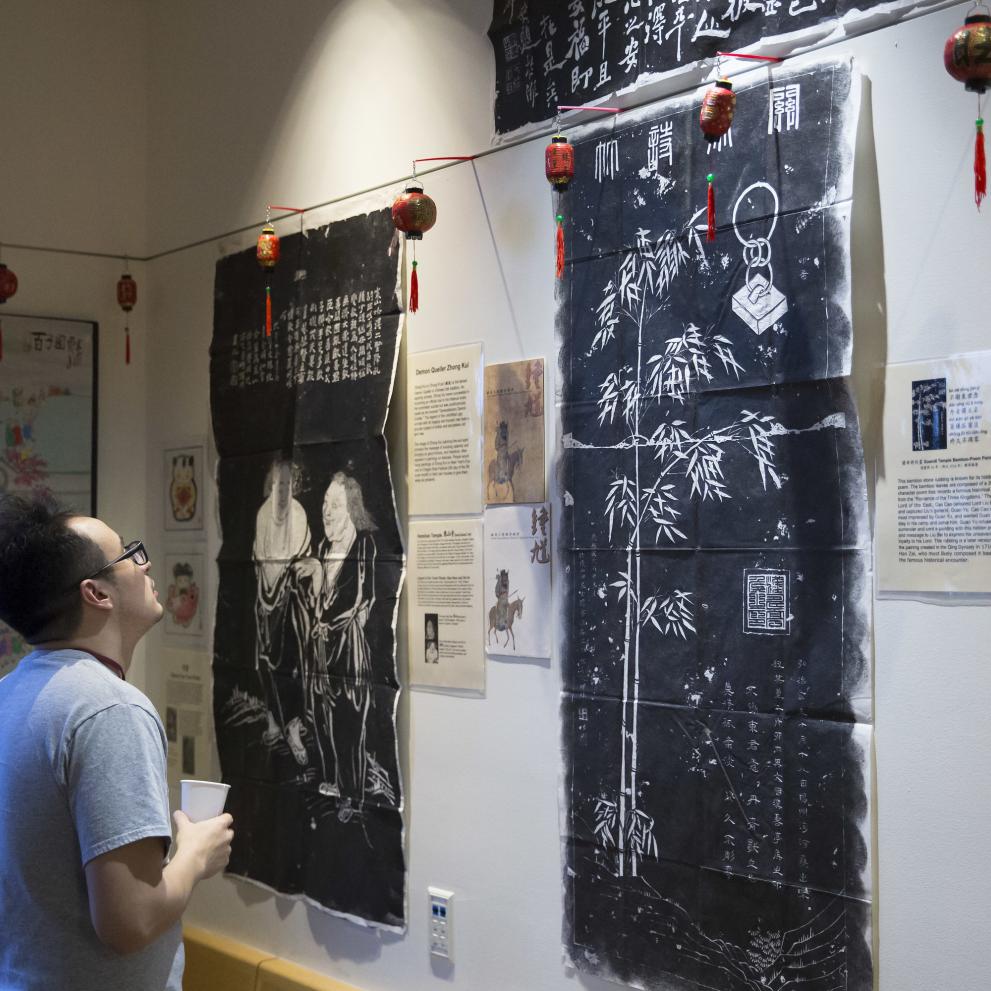 Student examining an Asian art exhibit