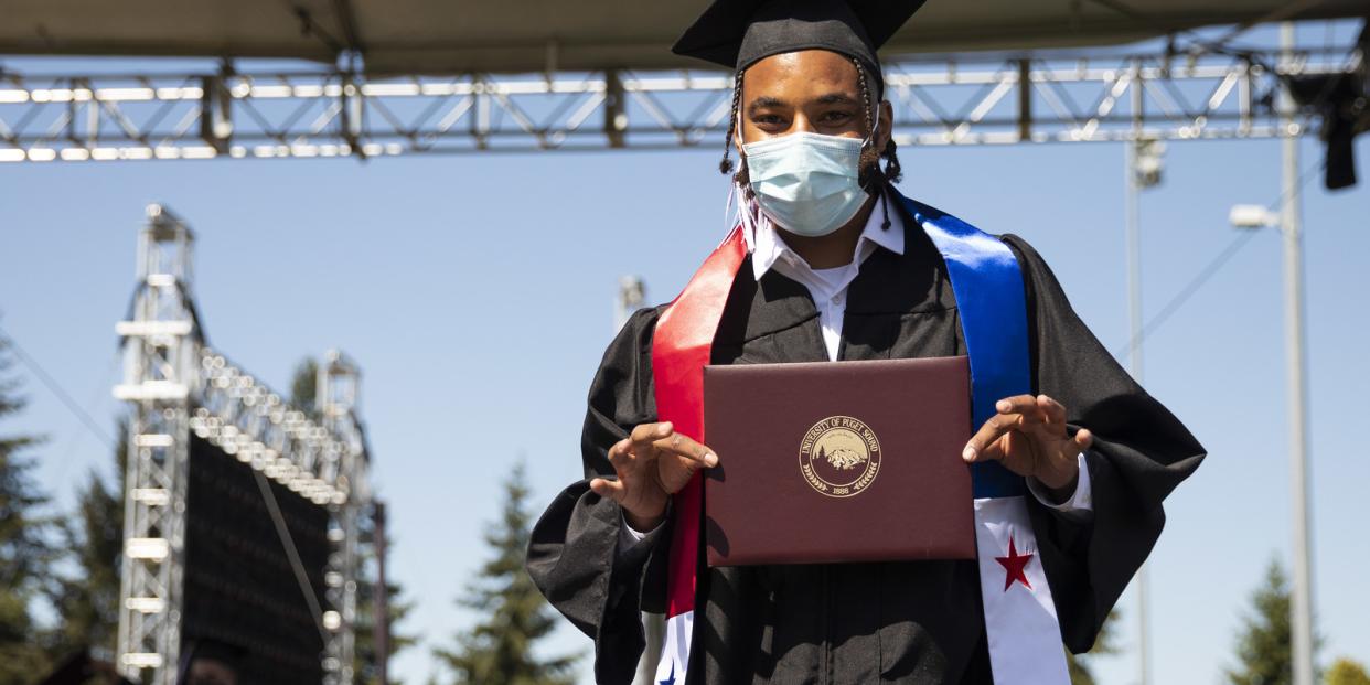 A graduate holds his diploma folio for the camera at Commencement 2021
