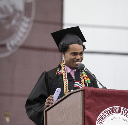 A graduate stands at the Commencement podium
