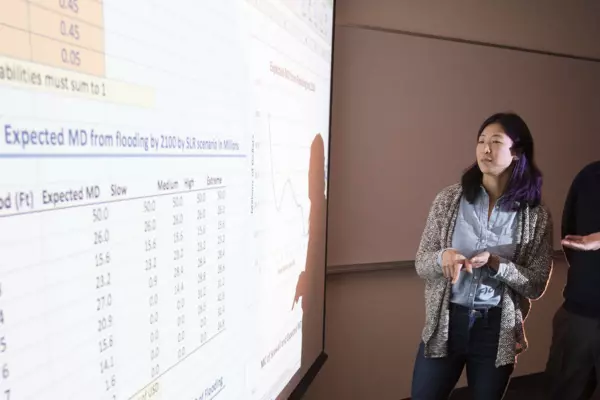Two people looking at a spreadsheet of data projected on a large screen