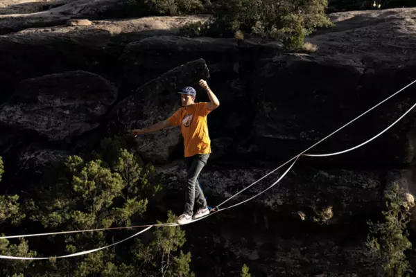 A person walking across a tightrope between two cliffs