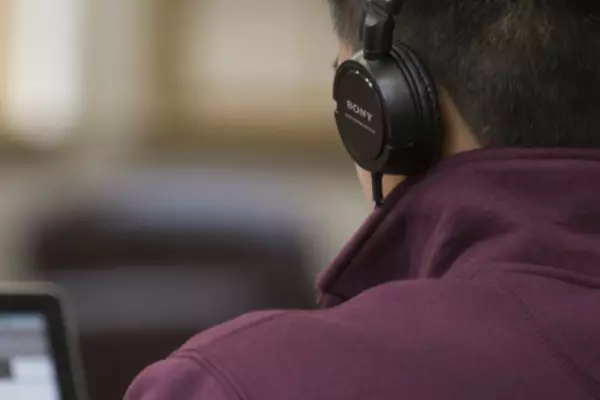 Person wearing headphones looking at a laptop