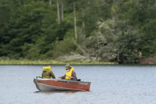 Two people sitting in a boat on a lake
