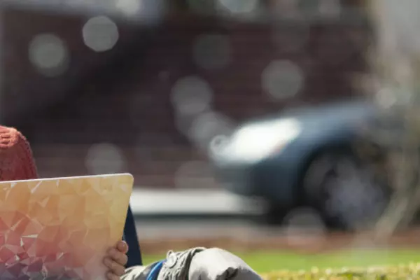 Person with laptop sitting on a park bench