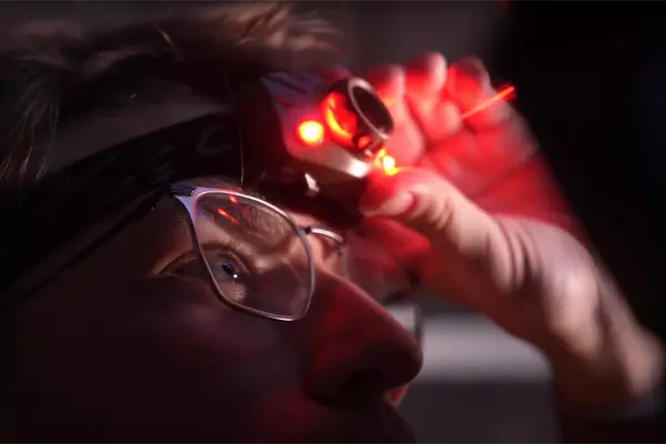 Austin Glock uses a red head lamp to make adjustments in the university observatory.