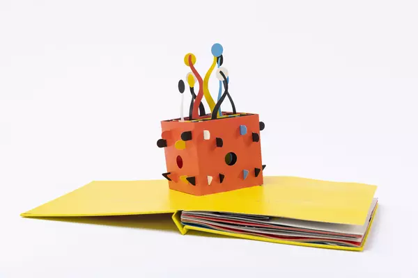 A pop-up book: a red cube with streamers coming out of it.