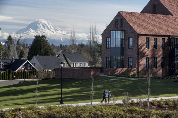 Students walk on campus with Mount Rainier in the distance.
