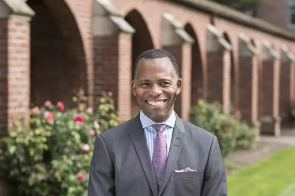 President Isiaah Crawford smiles at the camera as he stands in front of the campus arches. 
