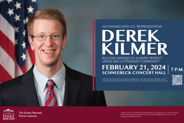 Derek Kilmer stands in front of an American flag smiling.