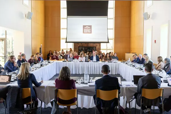 Trustees sit at tables in a circle. 