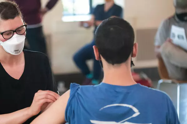 A shot clinic on campus where a student receives a vaccination.