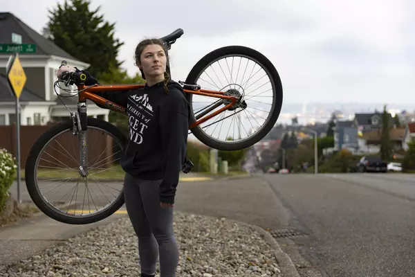 Emma Smith ’24 with her bike over her shoulder on N. 30th St. in Tacoma.