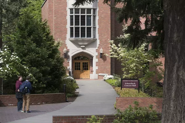 Red brick building with large yellow door under a window. 