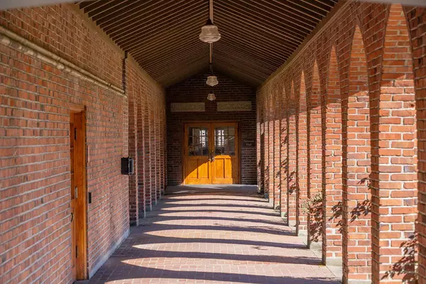 red brick hallway with arches to the right and double doors at the end. 