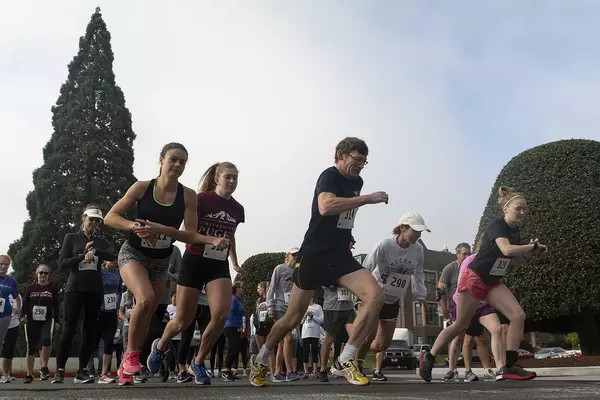 A group of runners in front of a giant sequoia tree