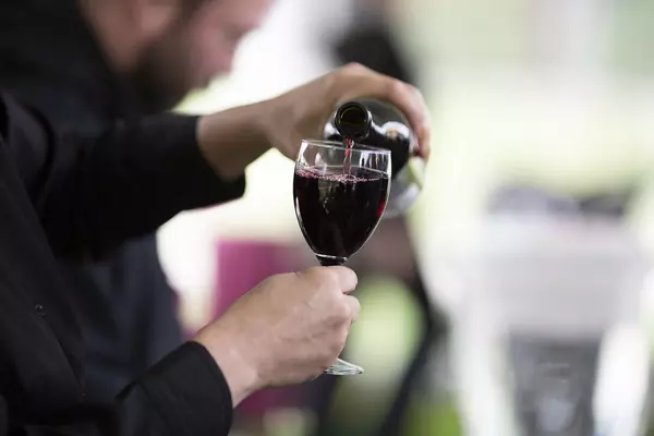 A glass of red wine being poured.