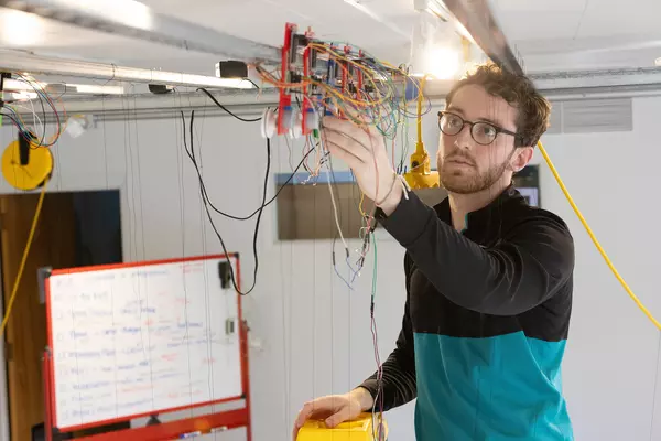 Josh Cunningham ’25 examines one of the stepper motors powering his kinetic sculpture.