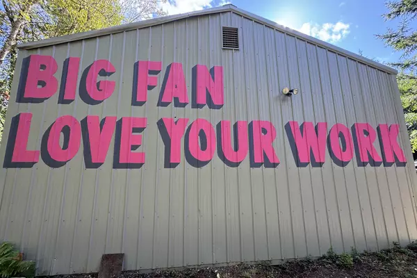 The words "Big Fan Love Your Work" painted on the side of a metal building.