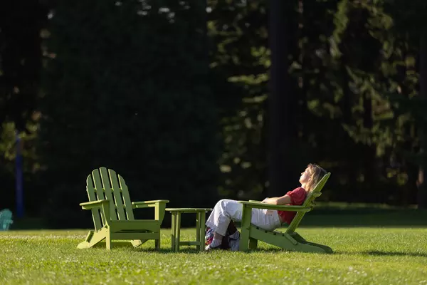 Student enjoys the sun while sitting in an Adirondack chair.