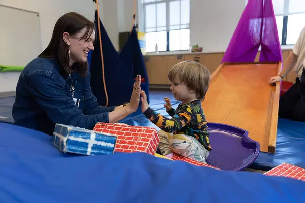 A woman gives a toddler a high five.