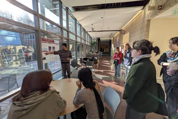 A student points at a science poster as a group of students look on. 