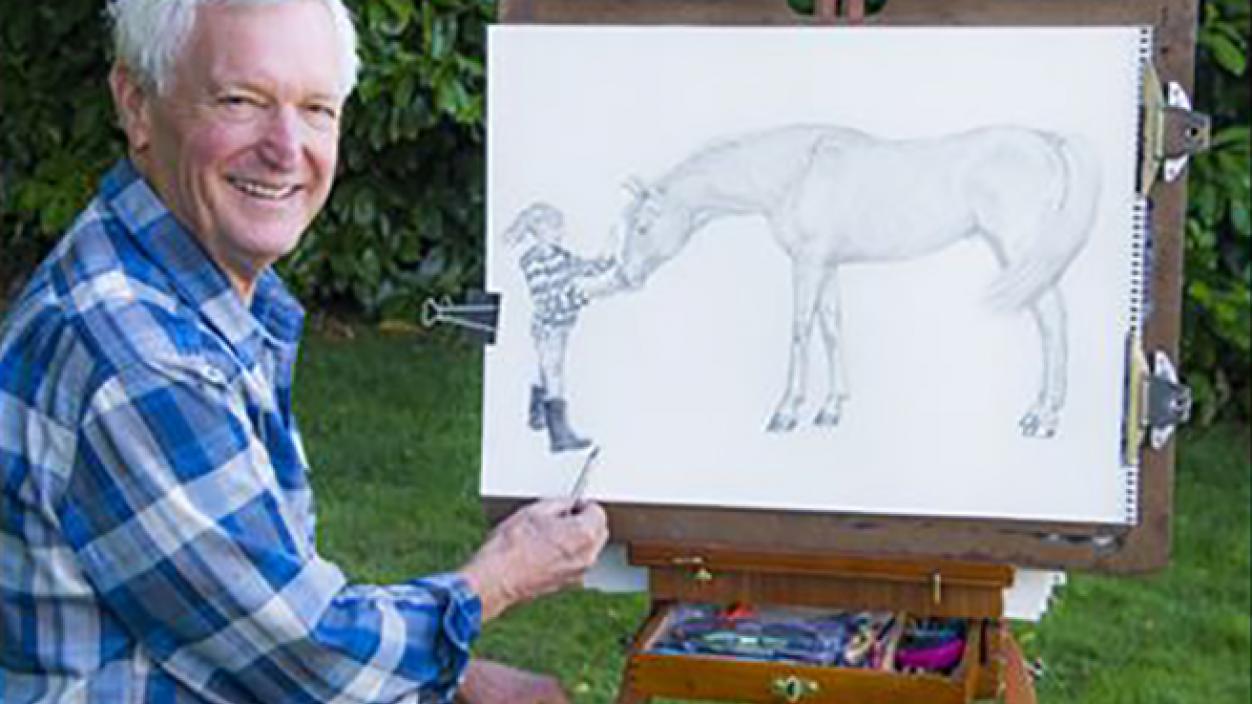 Man sitting outside and sketching a picture of a horse