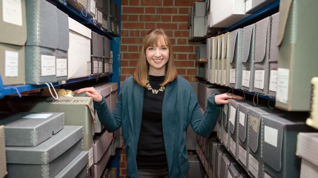 Woman standing between two shelves of archive boxes